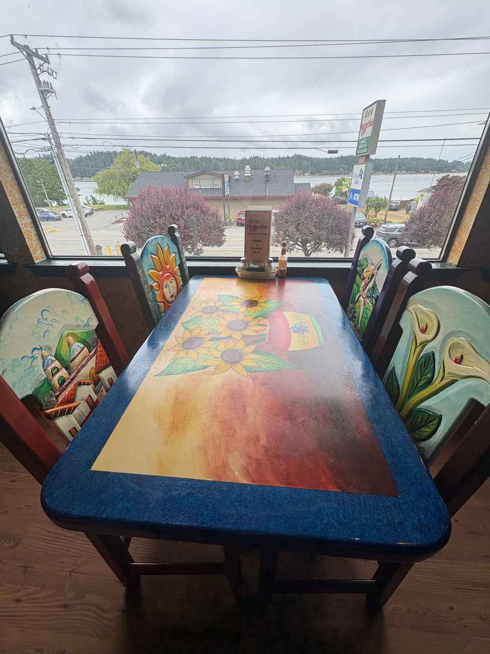 Dining table beside a large window at 2 Margaritas Allyn with a view toward the surrounding waterfront area